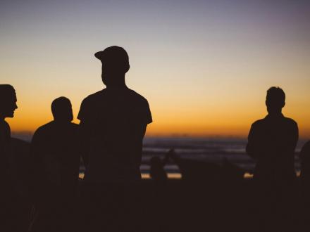 Jongeren op het strand bij zonsondergang