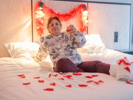 Vrouw viert in hotelkamer met glaasje bubbels